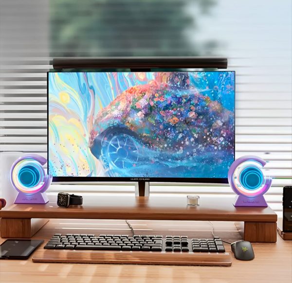 Colorful desktop setup featuring a monitor, RGB speakers, and keyboard, enhancing a vibrant workspace.